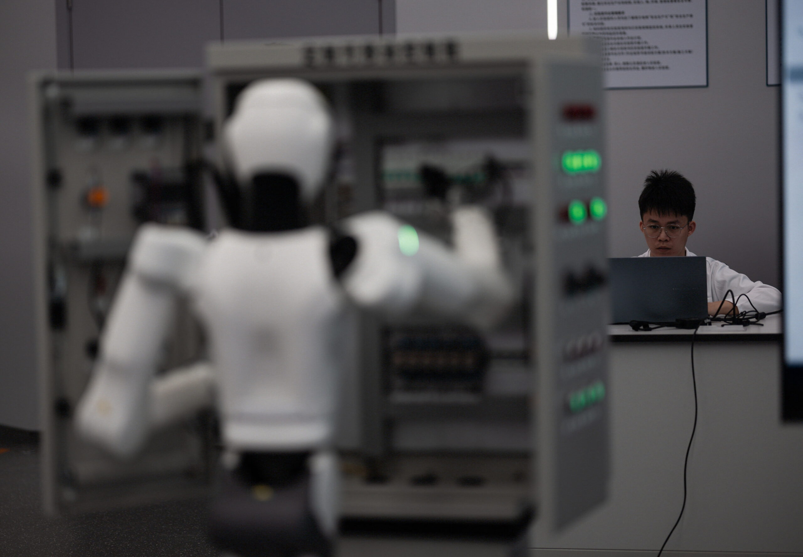 epa12894303 An employee trains service robots in a Southern Power Grid company laboratory during a government-organised visit in Guangzhou, Guangdong province, China, 16 April 2026. China Southern Power Grid has highlighted its use of advanced AI technologies in power-sector applications, including computer vision, large language models, robotic process automation and humanoid robots.  EPA/ALEX PLAVEVSKI